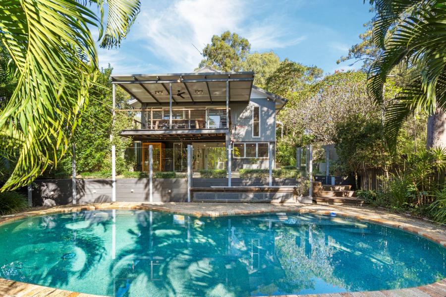 Daytime exterior of an elevated home with a kidney-shaped pool